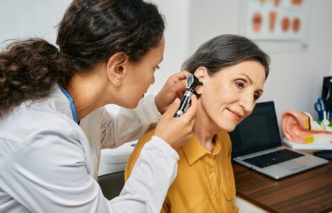Hearing exam for elderly citizen people. Otolaryngologist doctor checking mature womans ear using otoscope or auriscope at medical clinic